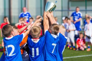 Young Soccer Players Holding Trophy. Boys Celebrating Soccer Football Championship. Winning team of sport tournament for kids children.
